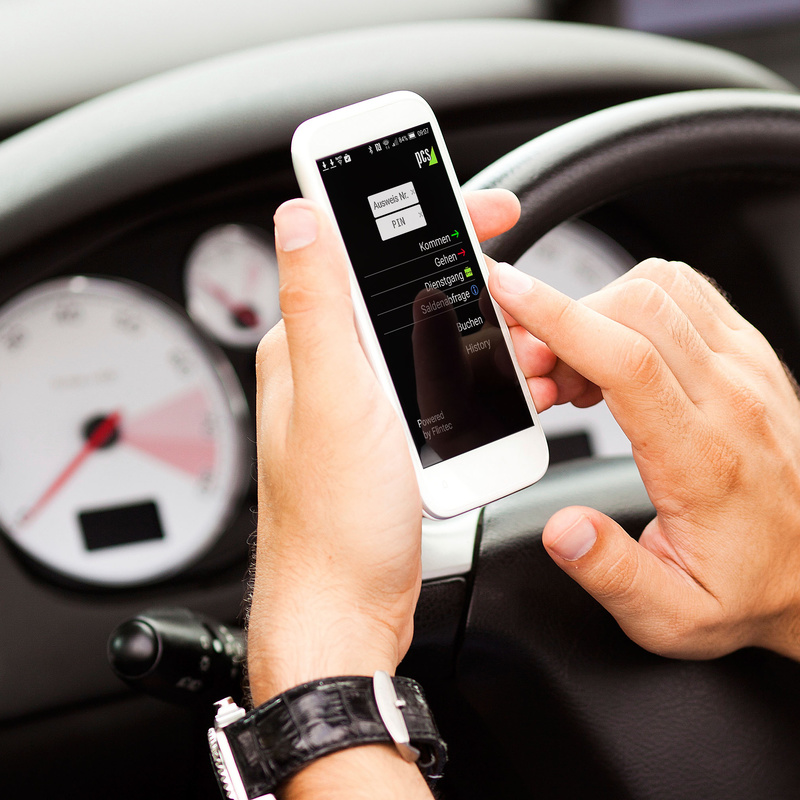 Mann im Auto, der auf einem Smartphone die Anwendung INTUS FTC mobile Zeiterfassung bedient