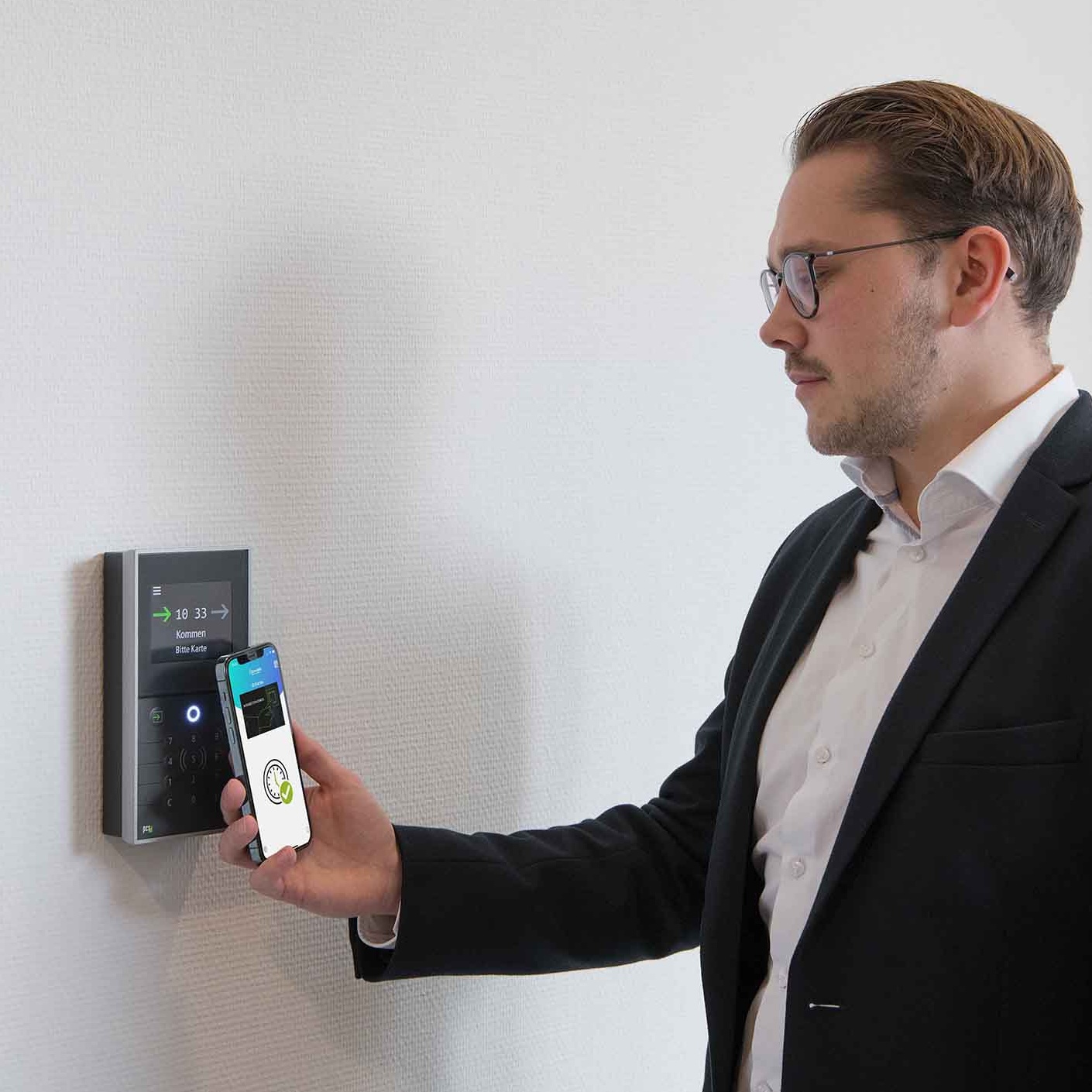 Mann bedient INTUS 5200 Zeiterfassungsterminal mit Smartphone