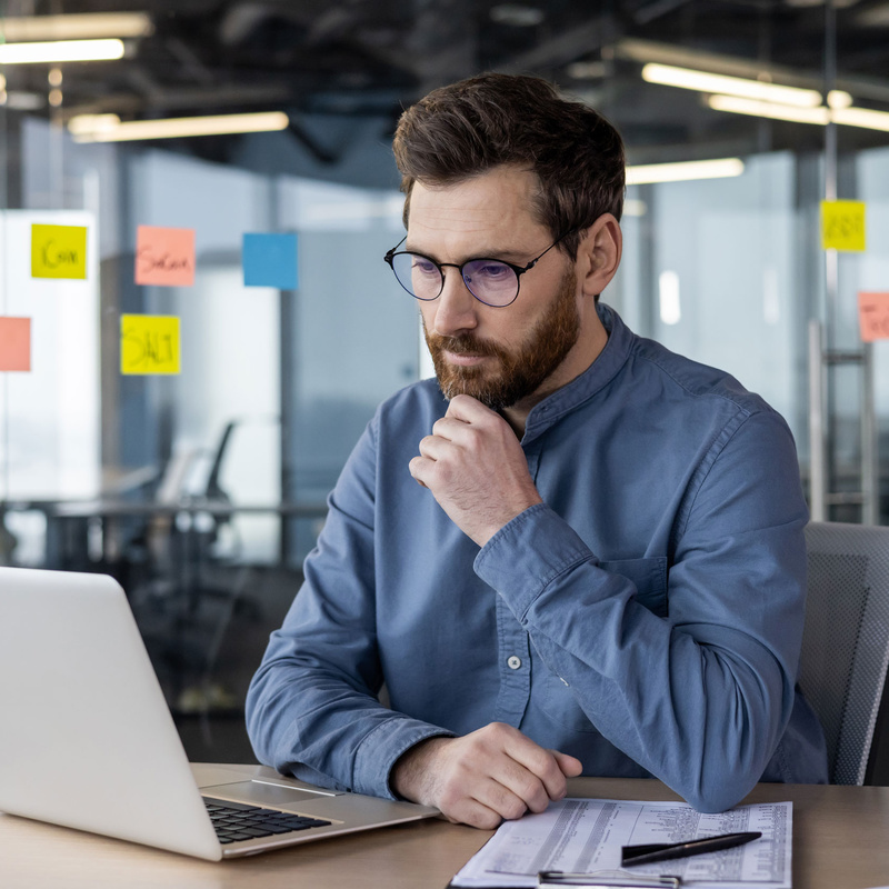 Person vor Laptop vor Glaswand mit post-it