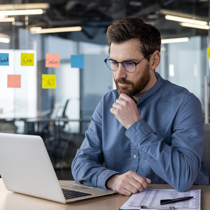 Person vor Laptop vor Glaswand mit post-it