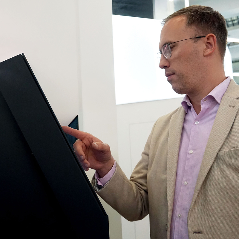 Person führt Selbstanmeldung an Kioskterminal durch
