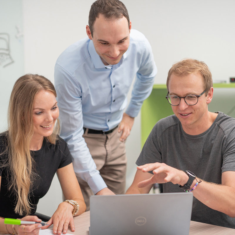 Drei Personen in Projektbesprechung vor Laptop