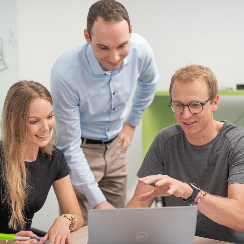 Drei Personen in Projektbesprechung vor Laptop