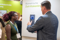 Der PCS Account Manager erklärt auf der Messe die Funktionsweise der Handvenenerkennung für Zutrittskontrolle.