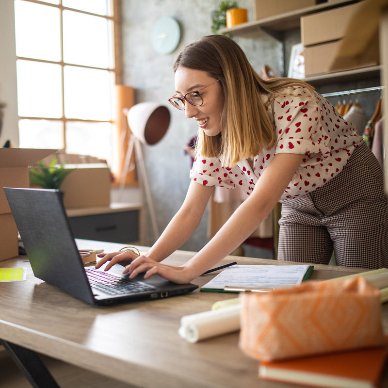 Frau stehend an Schreibtisch mit Laptop