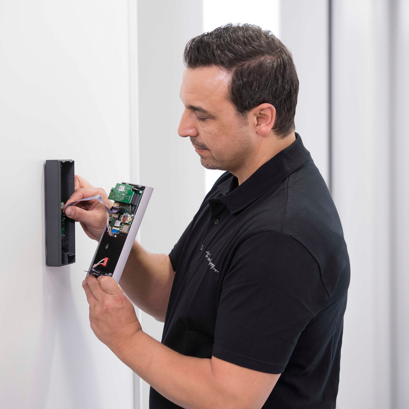 Servicetechniker montiert ein INTUS 5200 Zeiterfassungsterminal an einer Wand.