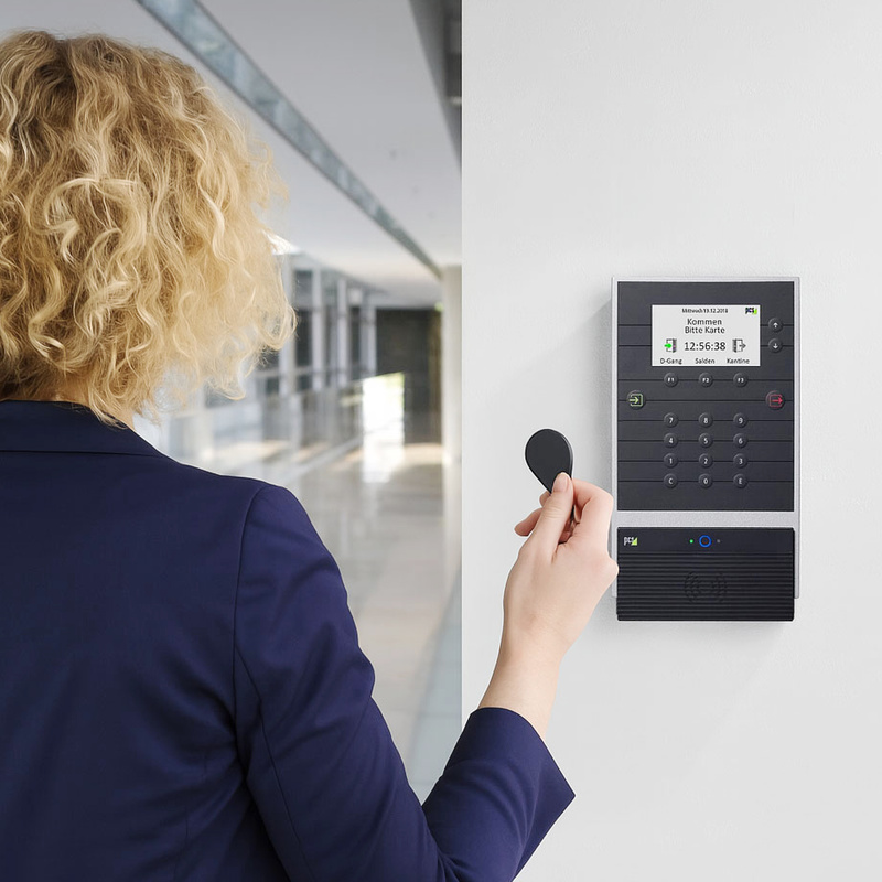 Frau bucht Arbeitszeit an INTUS 5540 an Wand wird mit RFID-Tag