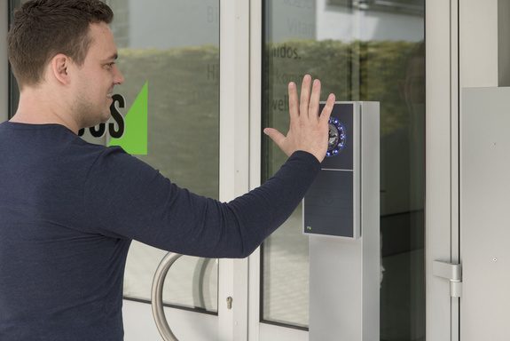 Mann hält seine Hand vor einen INTUS 1600PS Handvenenleser an einer Tür